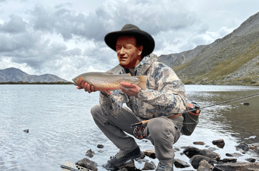 Angler holding a cutthroat trout with John Wayne's likeness.