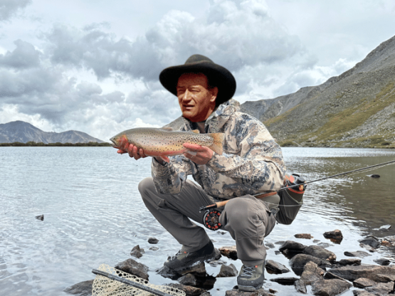 Angler holding a cutthroat trout with John Wayne's likeness.