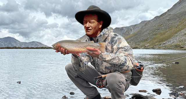 Angler holding a cutthroat trout with John Wayne's likeness.