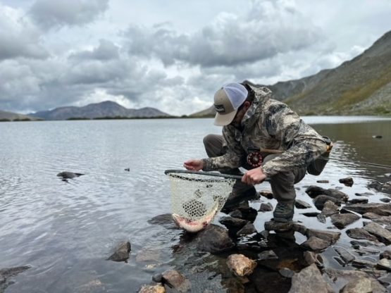 Angler at Ptarmigan Lake with a trout in the net.